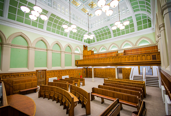 View of the Town Hall courtroom showing rows of seats, lights and window and ceiling details